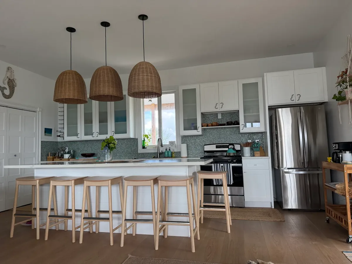 Full kitchen with island seating and rattan pendant lights at Blue Moon Cottage