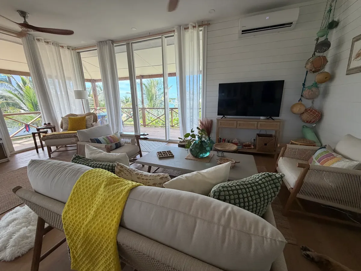 Bright living room with wraparound windows and water views at Blue Moon Cottage