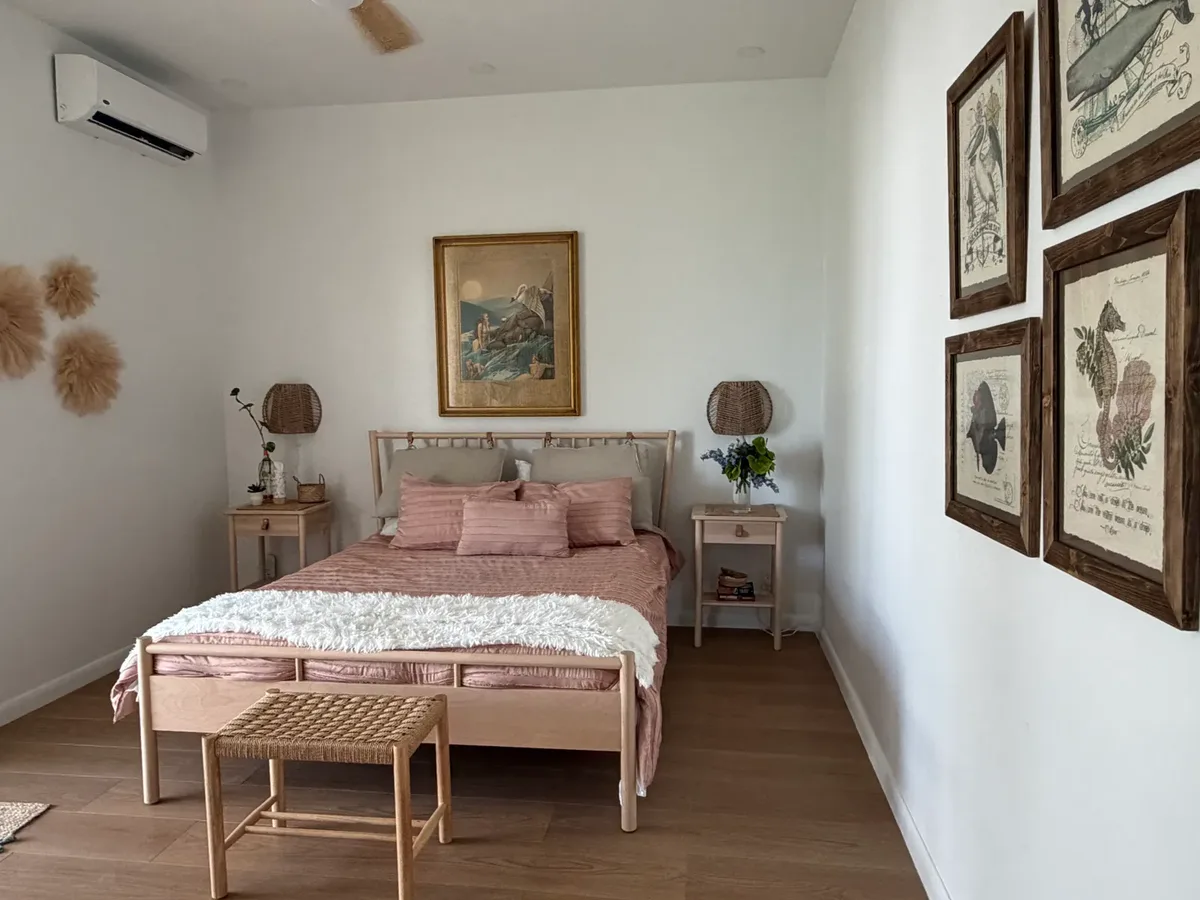 Queen bedroom with blush linens and framed sea-life prints at Blue Moon Cottage